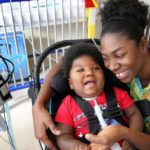 Antoinise Samuels with her 17-month-old son Samuel at their North Miami studio apartment. Samuel was born prematurely with microcephaly. He remains on a respirator and is fed through a G-tube. Samuel has outgrown his infant wheelchair, so transporting him has become increasingly difficult. The family is asking for a toddler wheelchair so he can get the help that might make it possible for him to one day attend school.