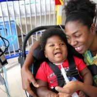 Antoinise Samuels with her 17-month-old son Samuel at their North Miami studio apartment. Samuel was born prematurely with microcephaly. He remains on a respirator and is fed through a G-tube. Samuel has outgrown his infant wheelchair, so transporting him has become increasingly difficult. The family is asking for a toddler wheelchair so he can get the help that might make it possible for him to one day attend school.